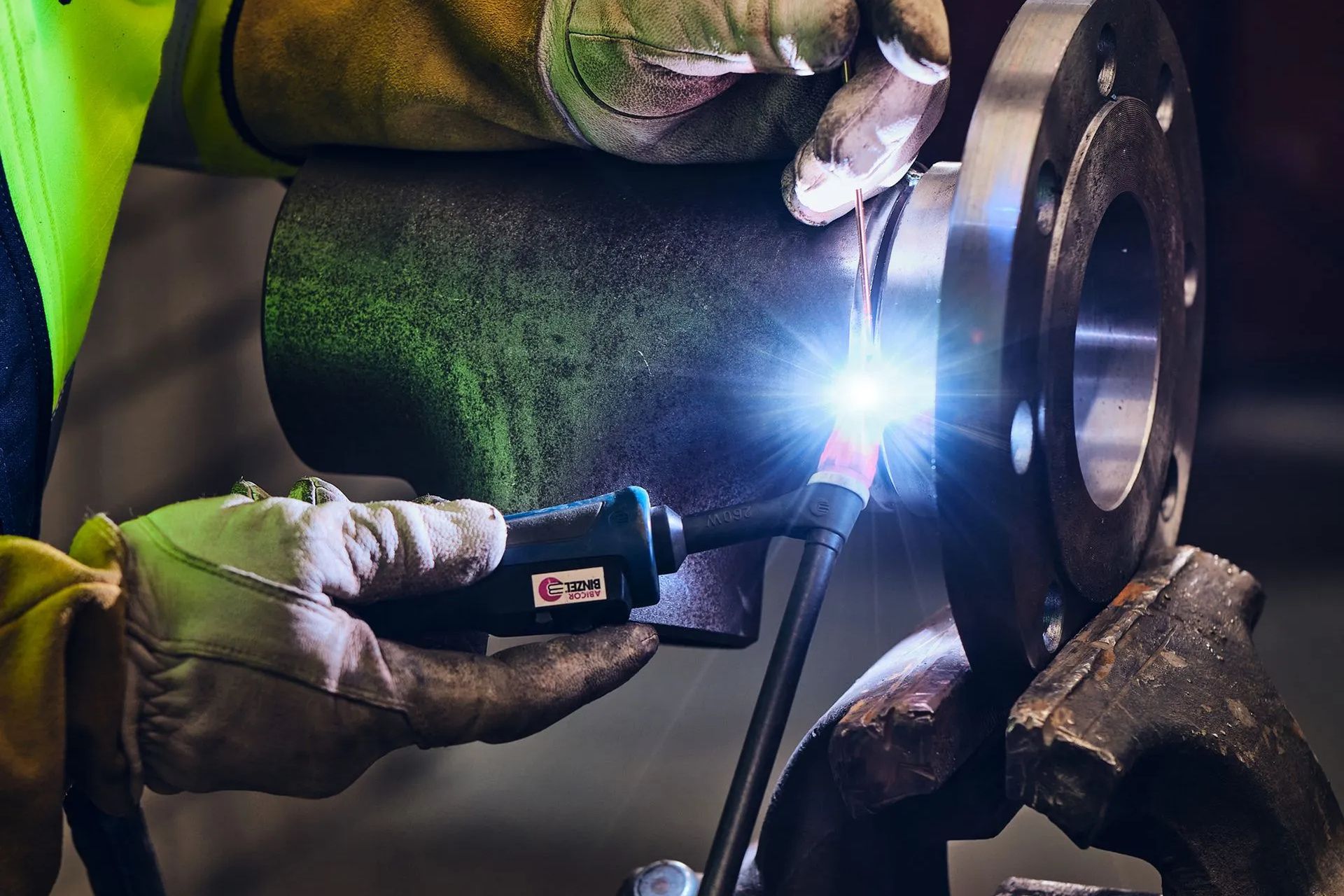 Man holding drone, looking at it, with monitors displaying aerial views, sitting at a desk.