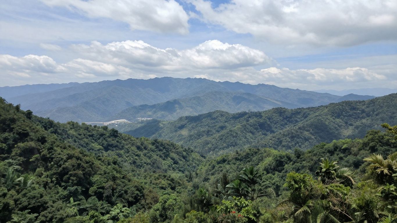 Lush green mountains under a cloudy blue sky, seen from a high overlook