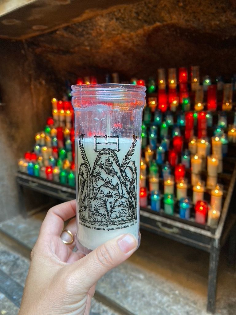 Una persona sostiene una vela delante de una fila de velas.