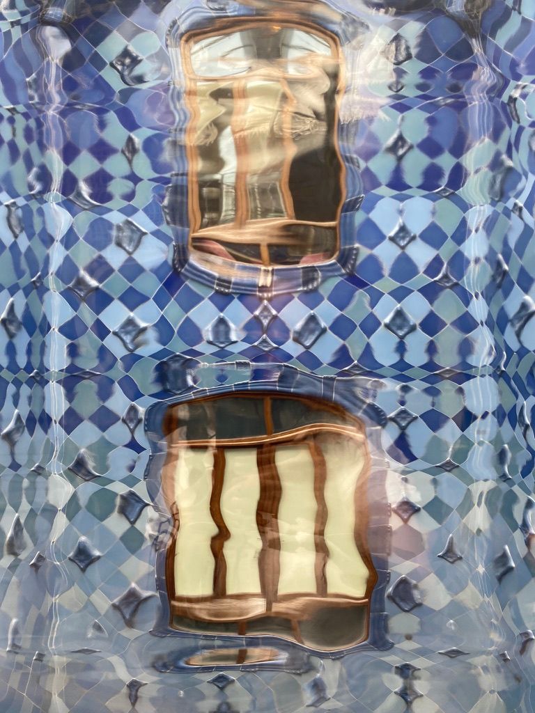 Un primer plano de un edificio con azulejos azules y el reflejo de una ventana.