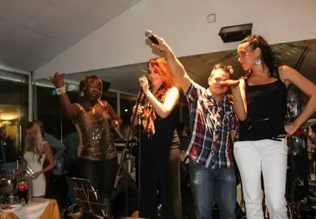 Un grupo de personas cantando con micrófonos en un escenario.