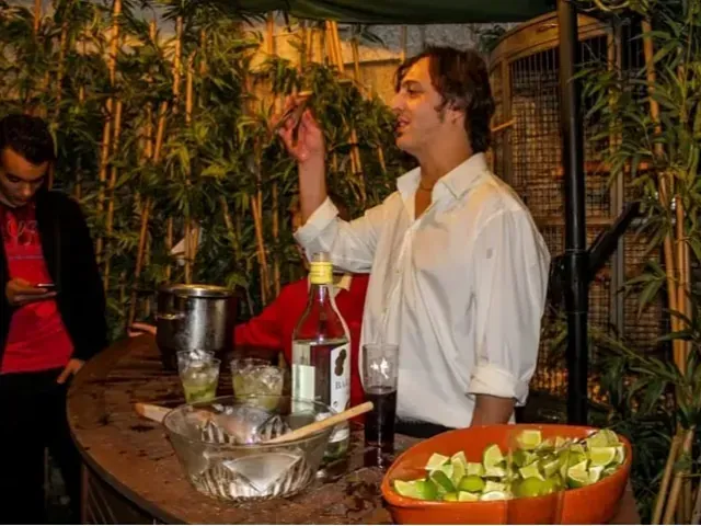 Un hombre con una camisa blanca está sirviendo una bebida en un vaso.