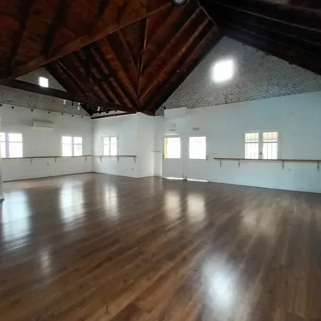 Una gran habitación vacía con suelos de madera y techo abovedado.