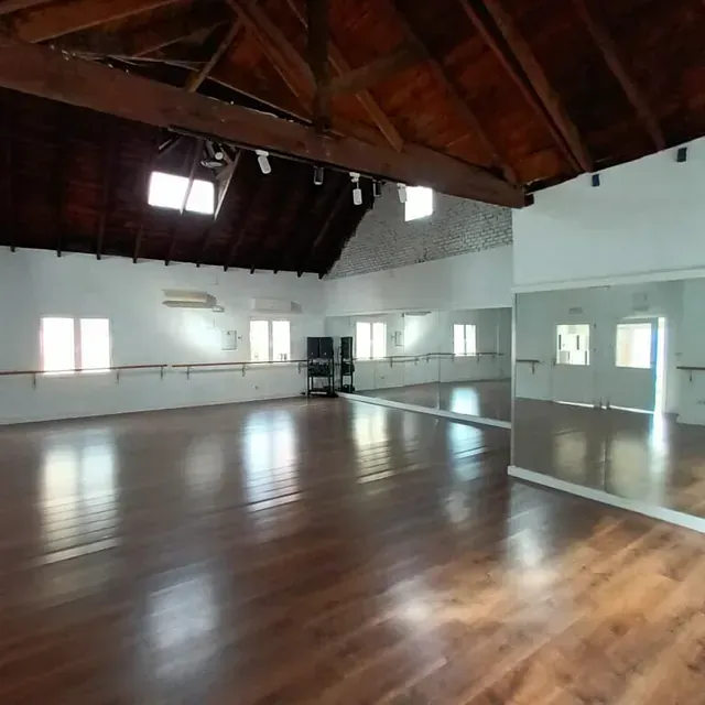 Un estudio de baile vacío con un gran espejo en la pared.