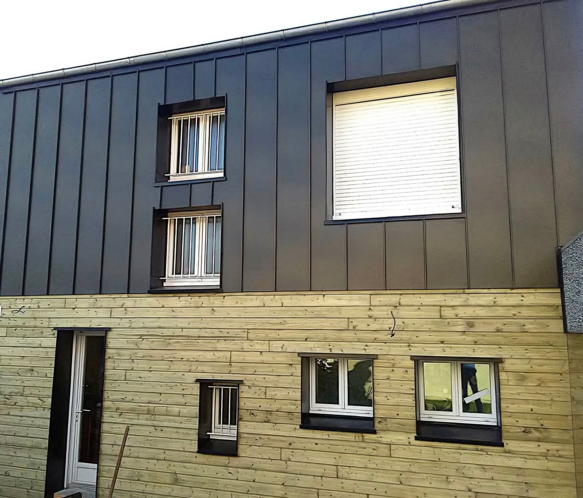 Bardage métallique noir sur un bâtiment.