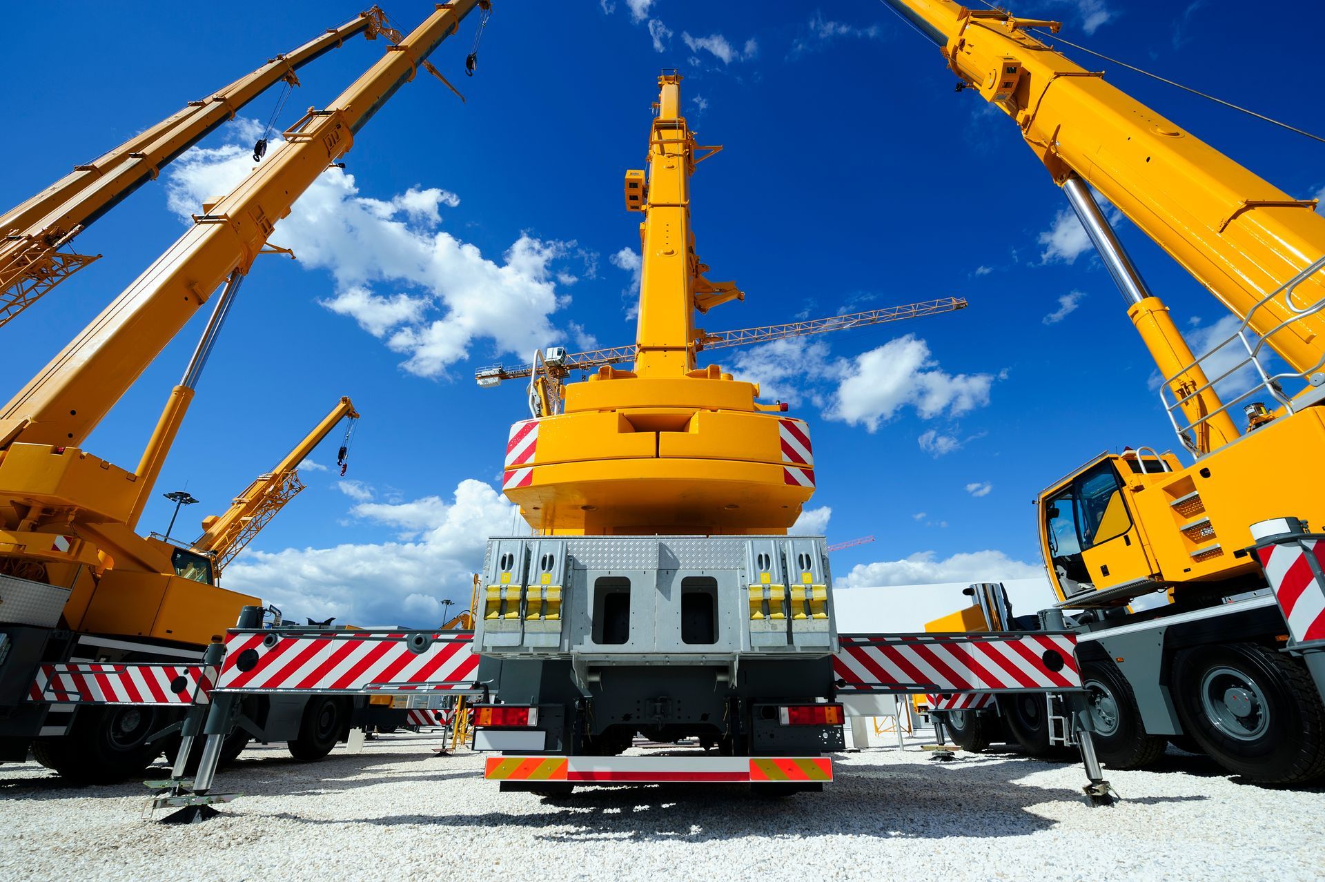 Gelbe Baukräne vor einem strahlend blauen Himmel, die zum Heben schwerer Lasten auf einer Baustelle verwendet werden.