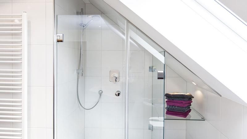 Ein Badezimmer mit Dusche und einem Regal mit Handtüchern darauf.