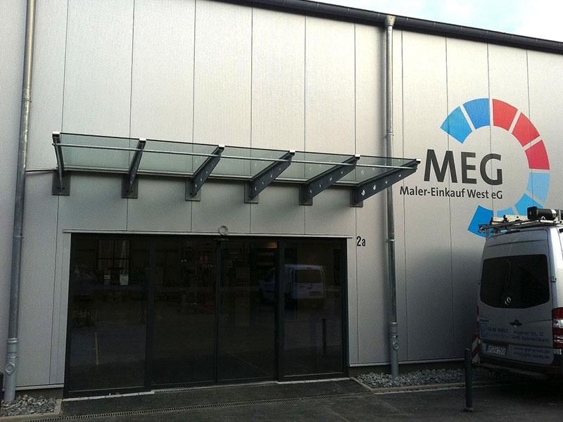 Ein Lieferwagen steht vor einem Gebäude mit der Aufschrift „Meg“