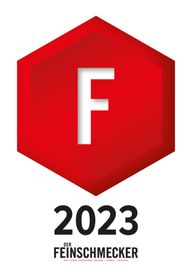 Rotes sechseckiges Abzeichen mit weißem „F“, „2023“ und dem Schriftzug „Der Feinschmecker“.