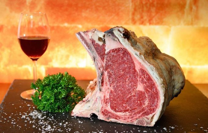 Eine Hand greift nach Strängen getrockneter Wurst, die in einem Laden hängen.