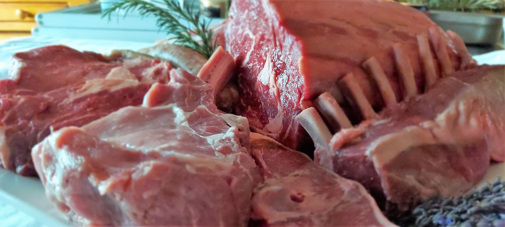 Eine Auswahl an rohen Fleischstücken, darunter ein Lammkarree, auf einer weißen Platte.