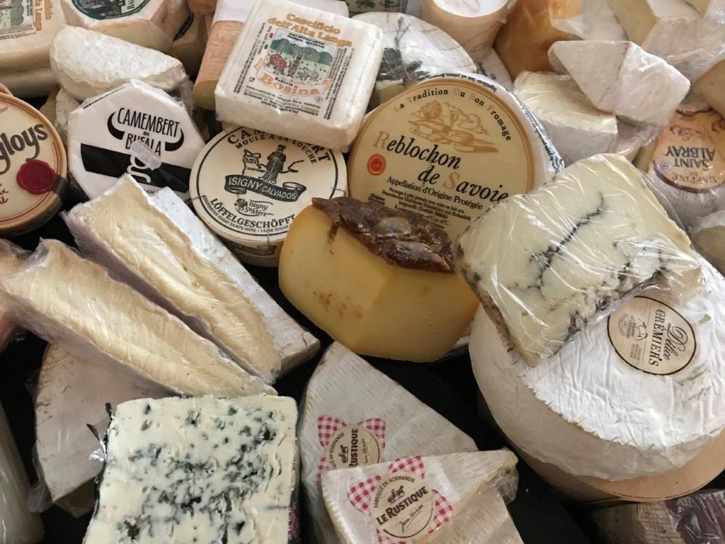 Sortiment verschiedener Käsesorten, darunter Blauschimmelkäse und Brie, teilweise verpackt.