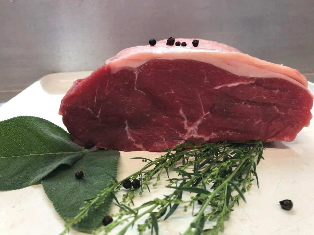 Roher Rinderbraten mit Fettschicht, Kräutern und Pfefferkörnern auf weißem Grund.