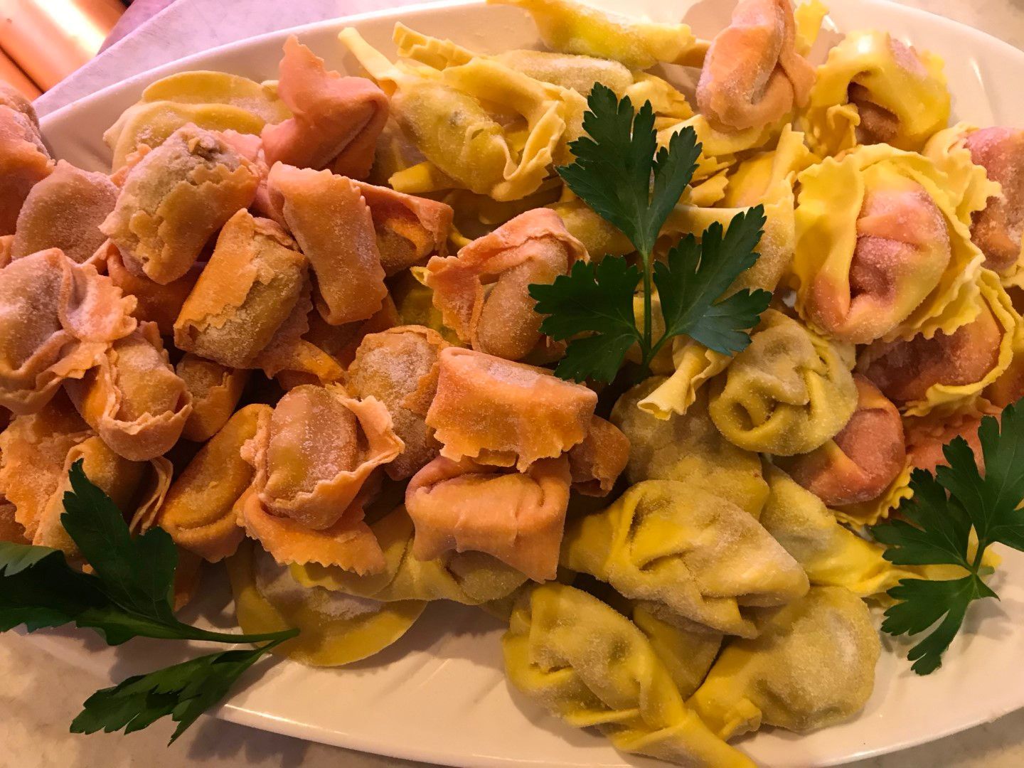 Eine Platte mit farbenfrohen Tortellini, garniert mit Petersilie.