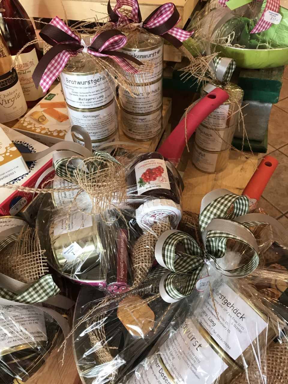 Geschenkkörbe mit Gläsern, Töpfen und Zutaten, in Zellophan verpackt und mit karierten Bändern verschnürt.