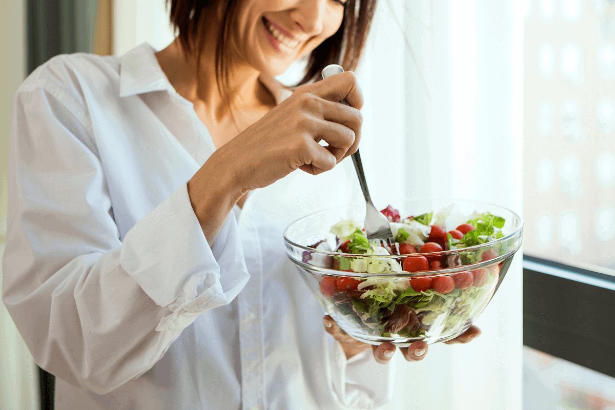 Eine Frau isst mit einer Gabel einen Salat aus einer Schüssel.