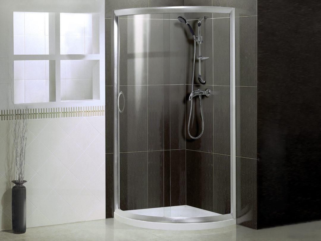 Ducha moderna a ras de suelo con azulejos grises, mampara de cristal y grifería cromada.
