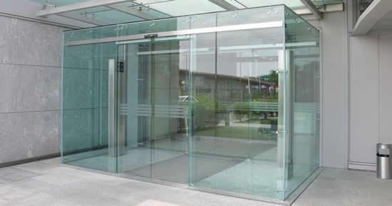 Vestíbulo de entrada con paredes de cristal y puertas correderas en el vestíbulo de un edificio moderno.