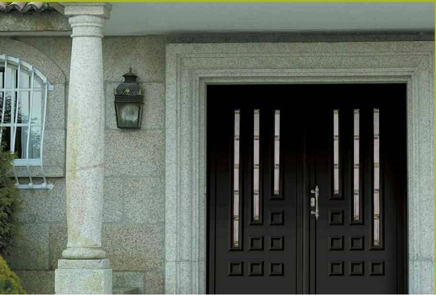 Entrada principal con puertas dobles oscuras y fachada de piedra junto a una ventana y una linterna de pared.