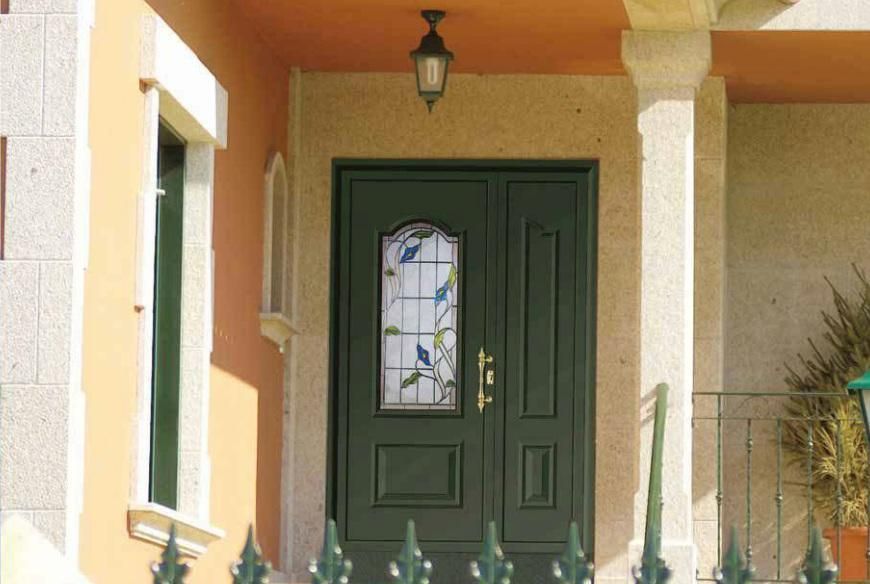 Porche delantero con puerta de entrada verde, panel de vidrio decorativo y paredes de estuco beige.