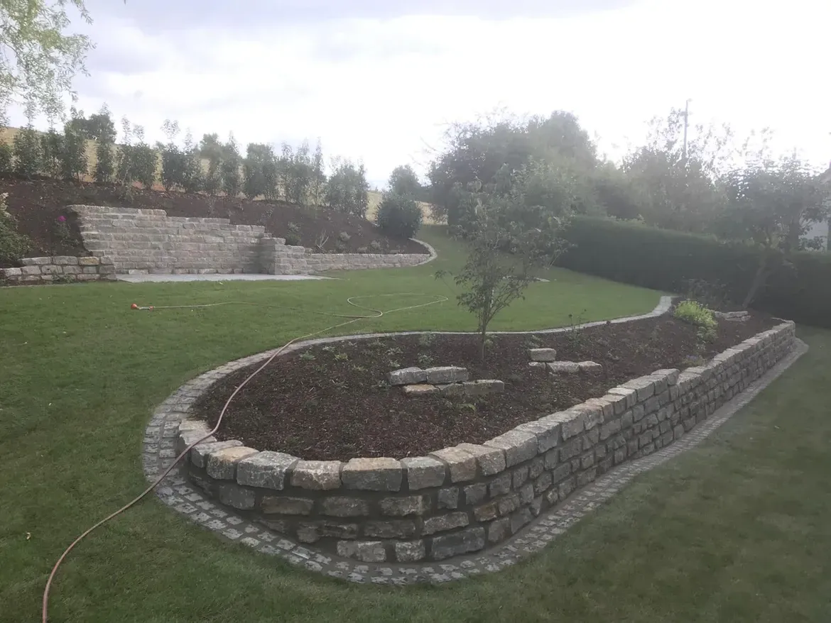 Inmitten eines üppigen grünen Feldes steht eine Steinmauer.