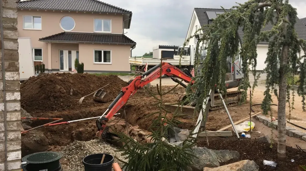 Eine Person hält eine Topfpflanze vor einem im Bau befindlichen Haus.