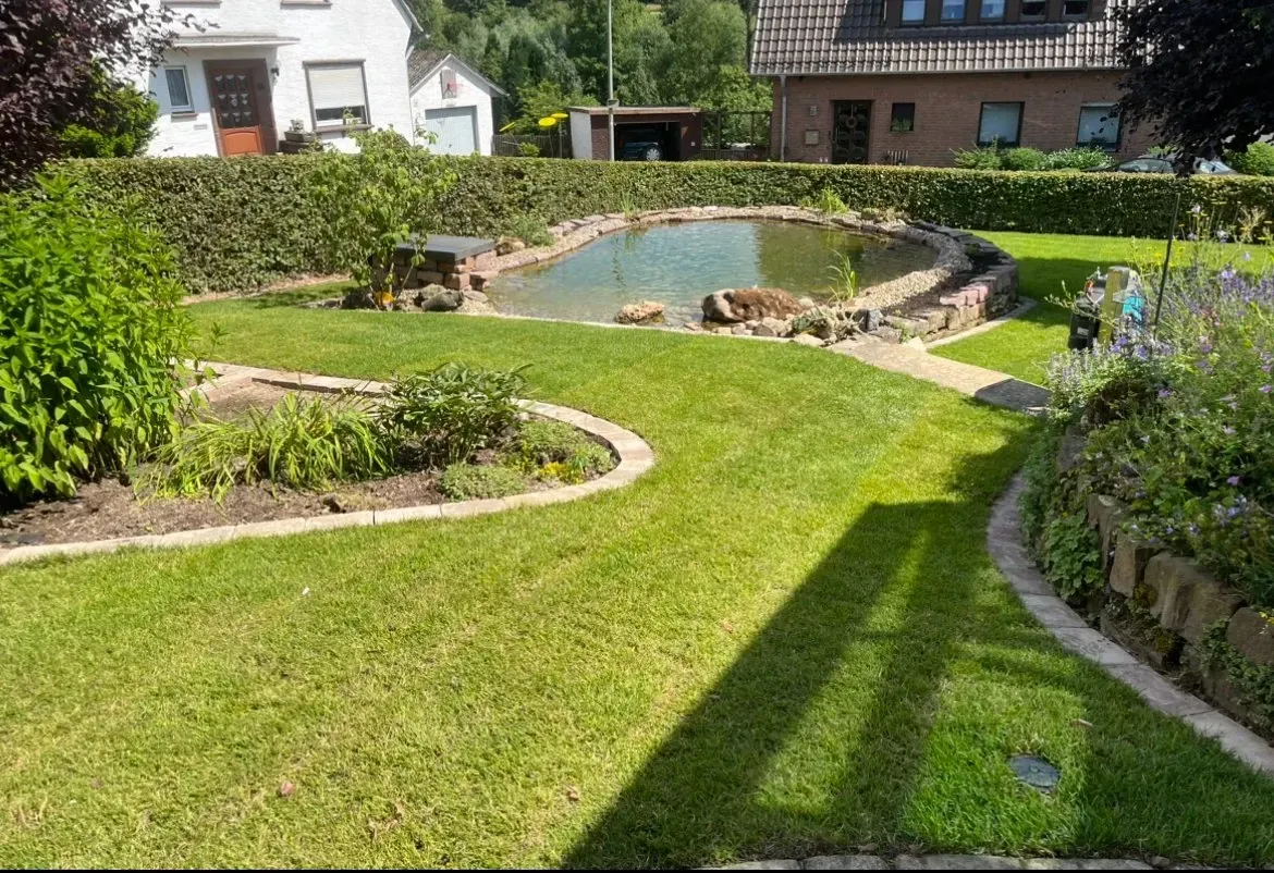 Ein üppiger grüner Rasen mit einem Teich in der Mitte.