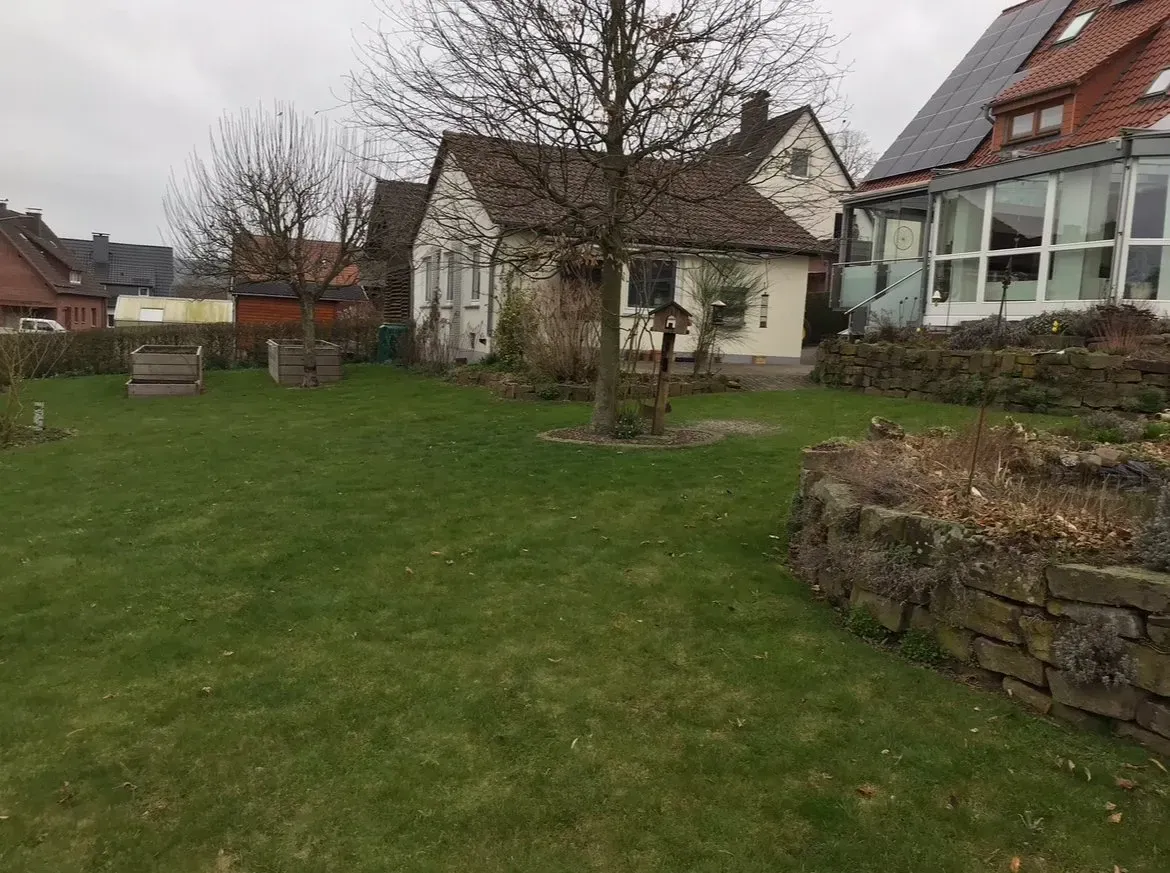 Ein großer, üppig grüner Garten mit einem Haus im Hintergrund.