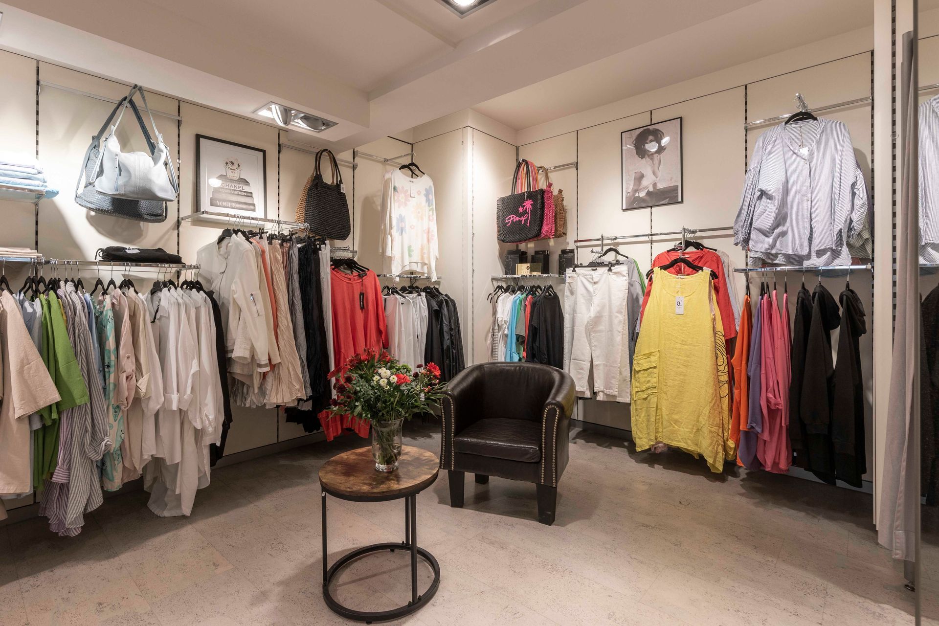 Eine Umkleidekabine voller Kleidung und einem Stuhl.