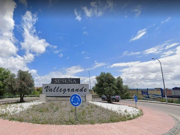Cartel indicativo de Sesena Vallegrande, zona residencial, en una rotonda bajo un cielo azul brillante.