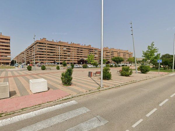 Una amplia plaza pavimentada frente a varios edificios de apartamentos de varios pisos bajo un cielo brillante y soleado.