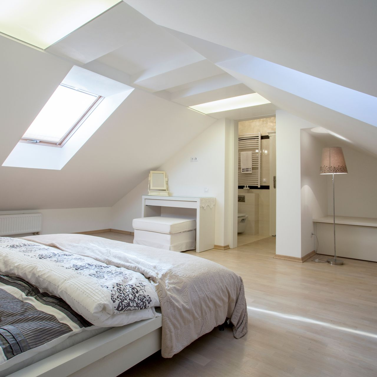 Chambre avec un puits de lumière, un lit et salle de bains en arrière-plan.