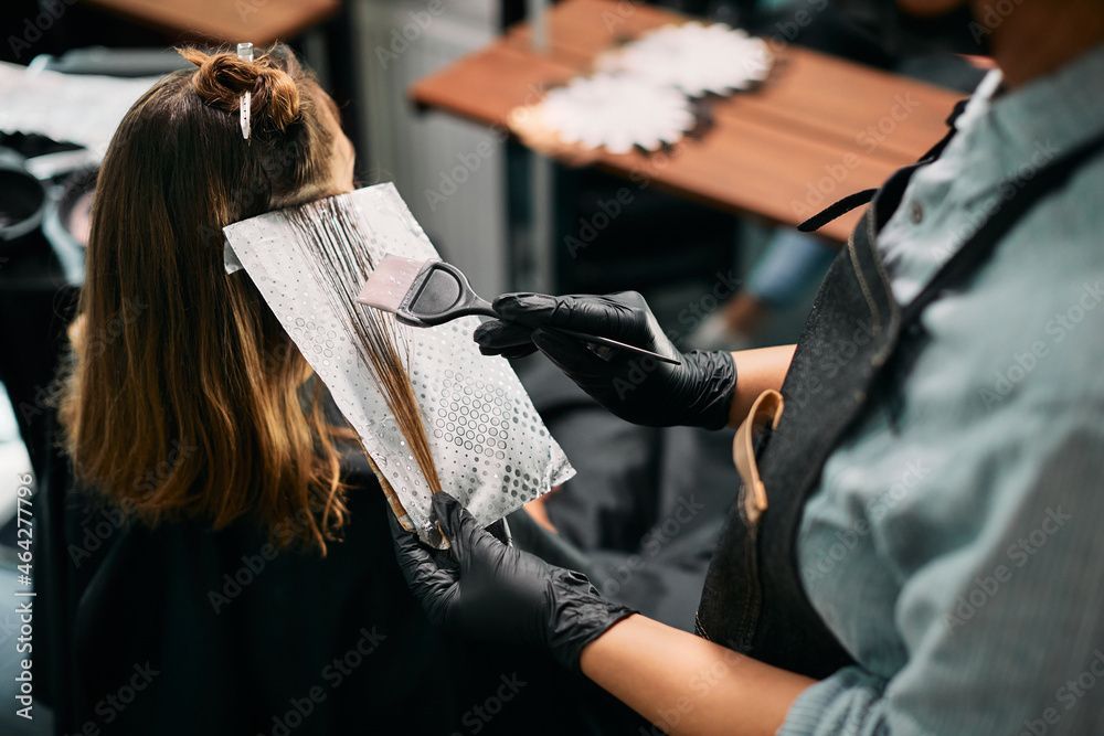 Eine Friseurin bringt in einem Salon Foliensträhnen im Haar einer Kundin an.
