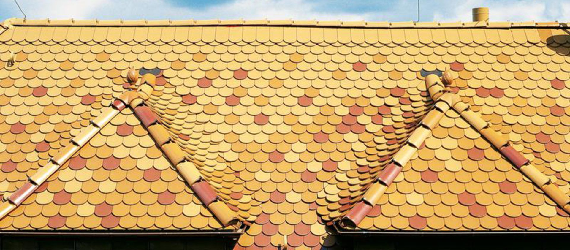 Detailliertes Dach mit farbigen Schindeln in Gelb und Orange – Arbeiten der Frank Sperling Dachdecker GmbH