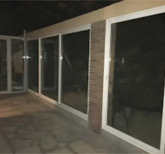 Un patio oscuro con grandes ventanales con marcos blancos. Una columna de ladrillo es visible entre las ventanas.