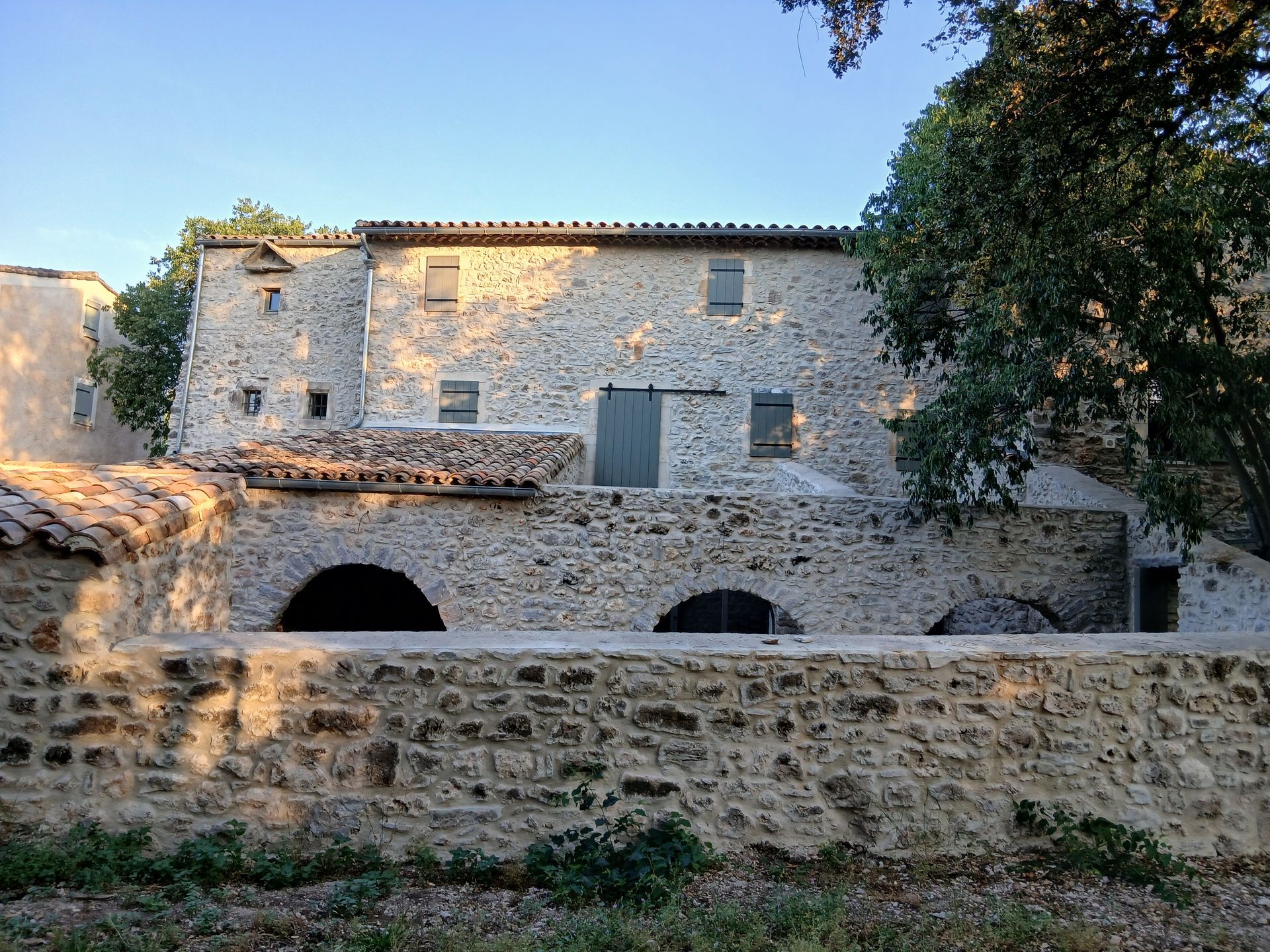 Bâtiment en pierre avec entrée cintrée et nombreuses fenêtres, ciel bleu en arrière-plan.