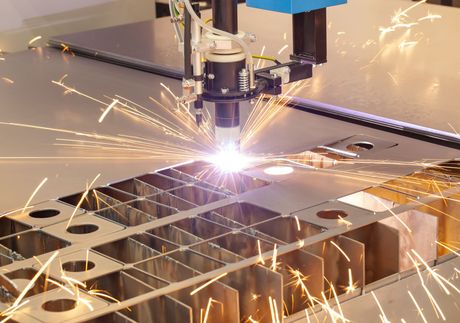 Découpe laser automatisée de tôles, créant des étincelles en usine.
