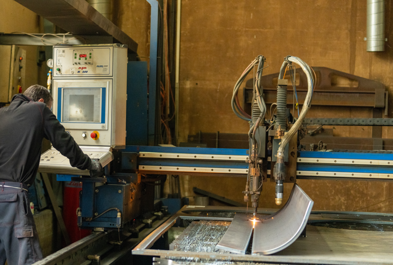 Une machine de découpe industrielle fait des étincelles au-dessus d'une tôle dans un atelier