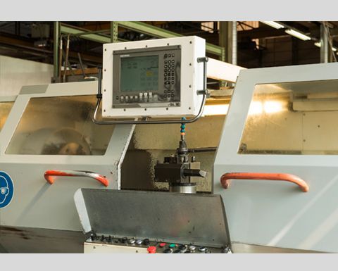 Tour CNC avec panneau de commande, situé dans un environnement d'atelier.