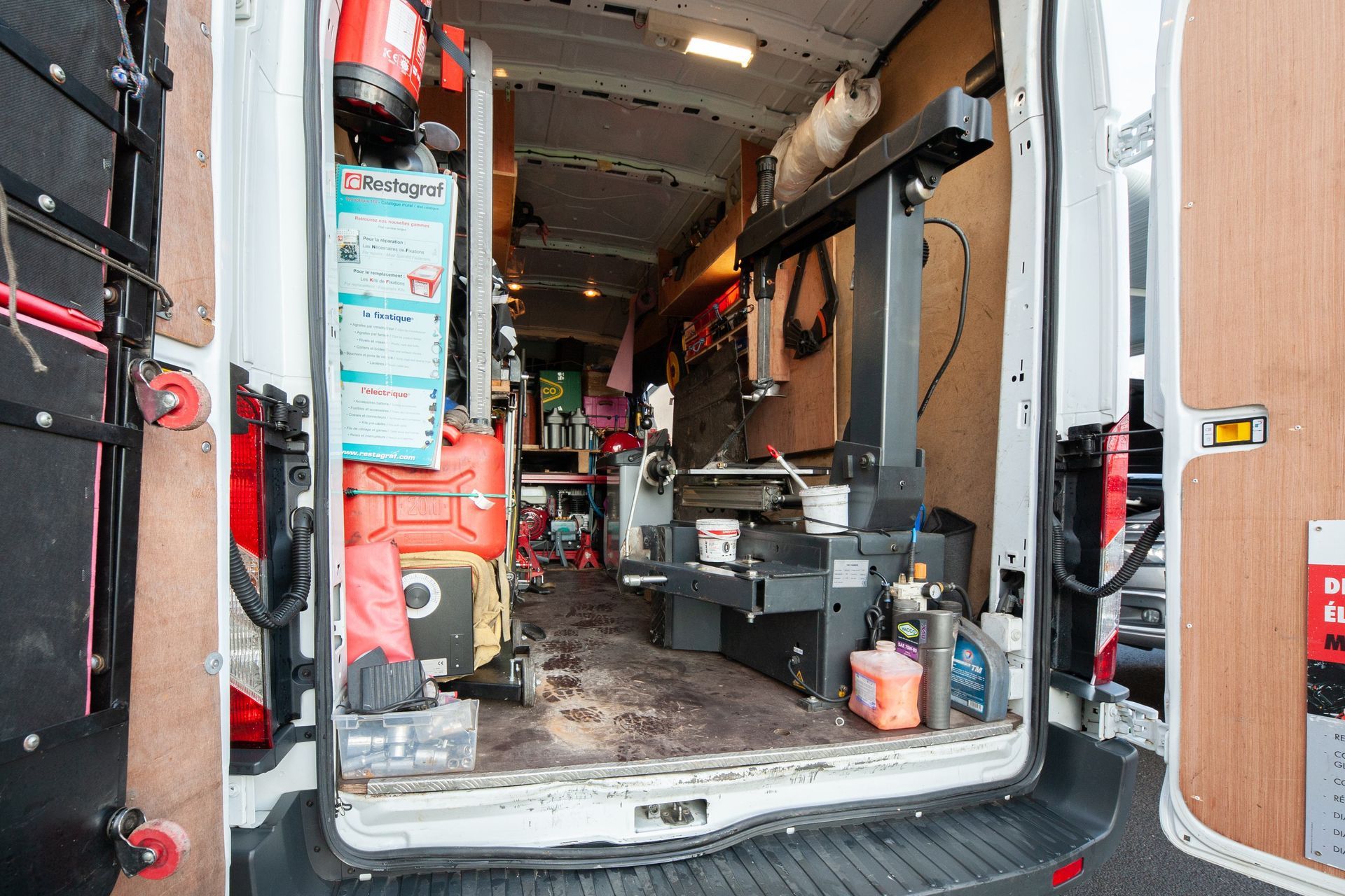 À l'intérieur d'une camionnette de travail, remplie d'outils et de machines, dont une machine à pneus.