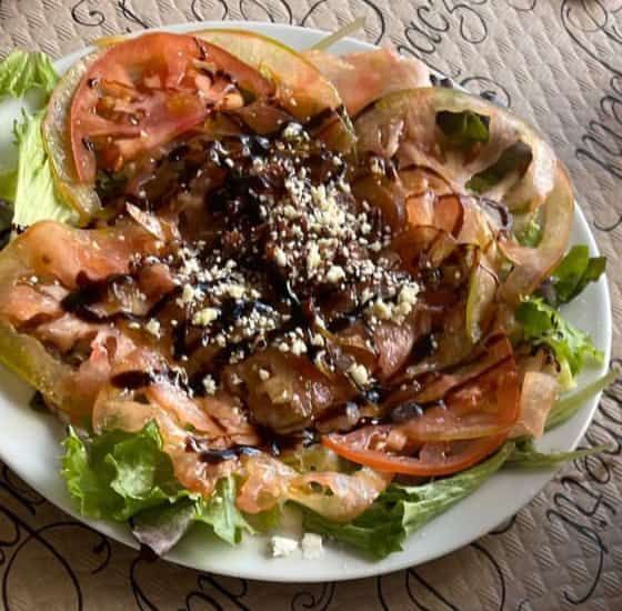 Ensalada con lechuga, tomates, salmón ahumado y queso desmenuzado en un plato.