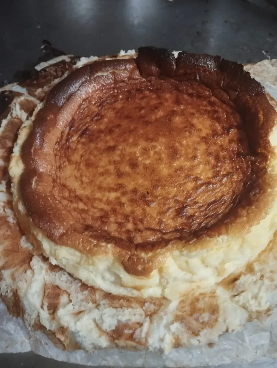 Soufflé o tarta de queso de color marrón dorado en una fuente para hornear, con una parte superior inflada y una masa blanca alrededor de los bordes.