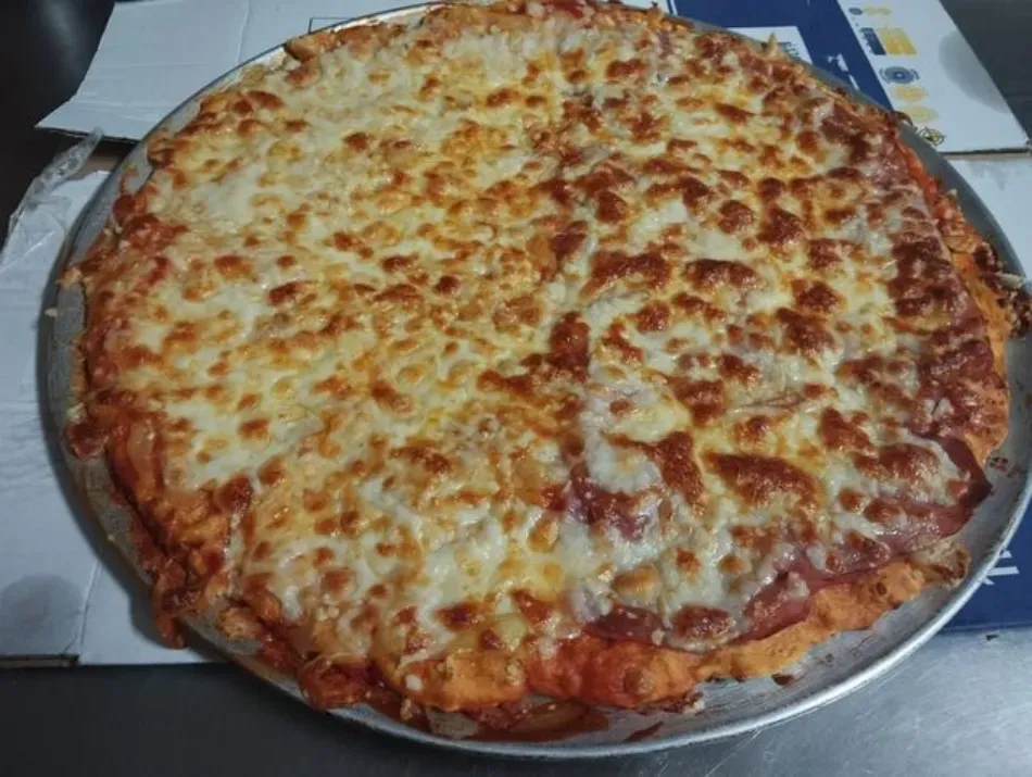 Pizza grande de queso en una bandeja redonda de metal con una capa superior dorada y burbujeante.