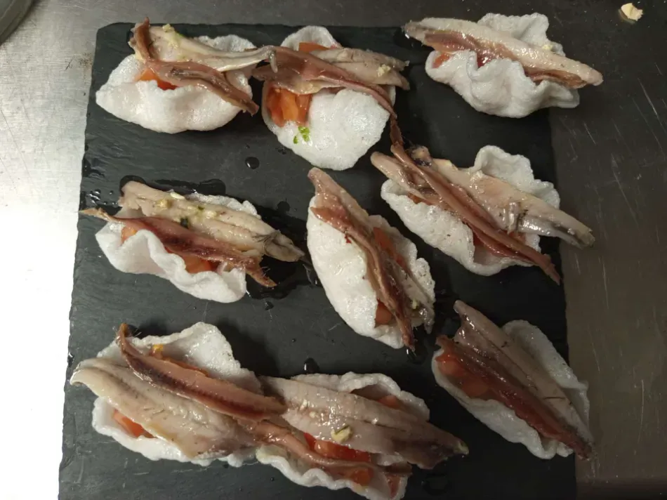 Nigiri de sushi cubierto con tocino, dispuesto en una tabla oscura.