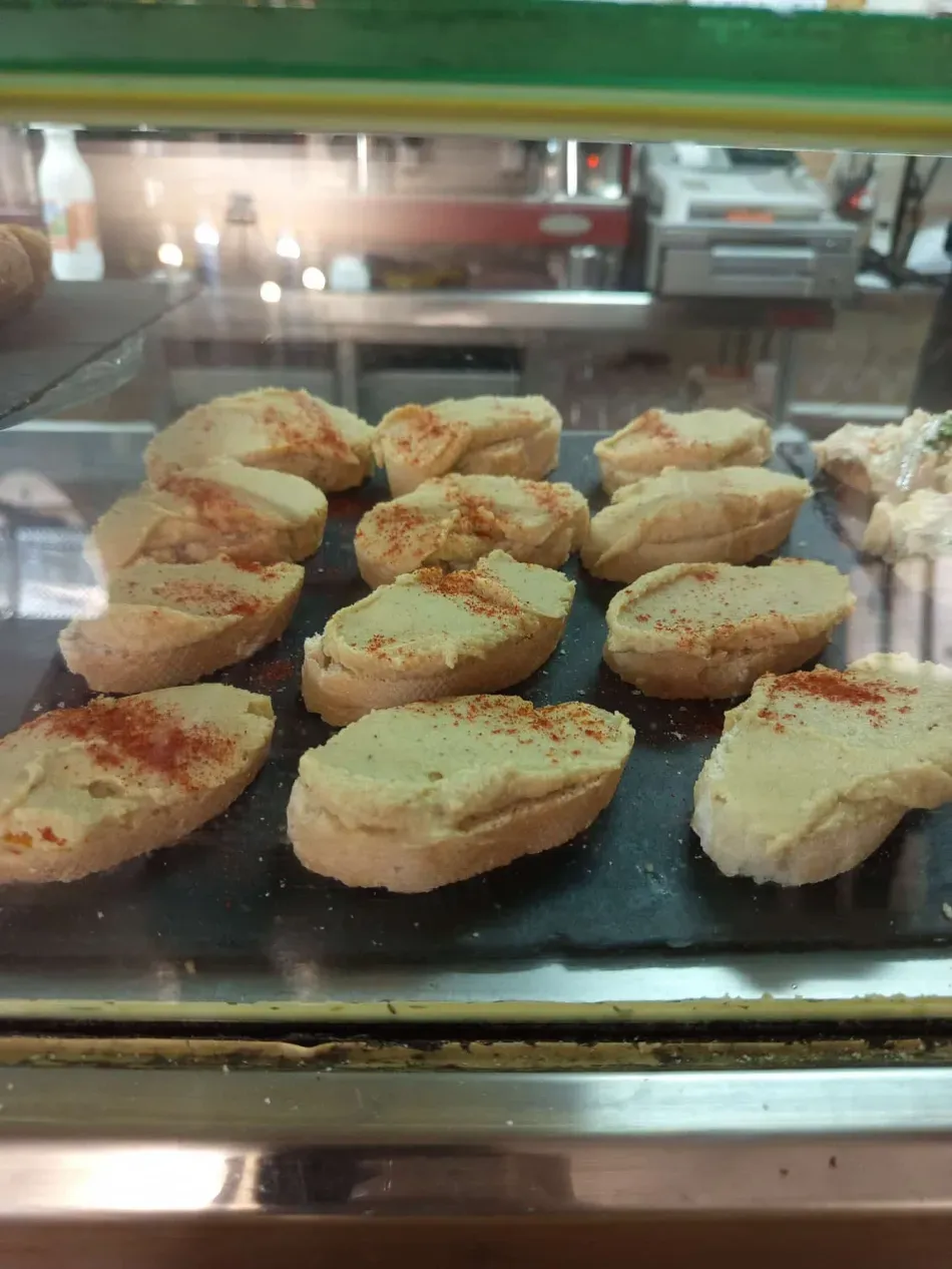 Bandeja de rebanadas de pan tostado con crema de ajo en una vitrina de cristal.