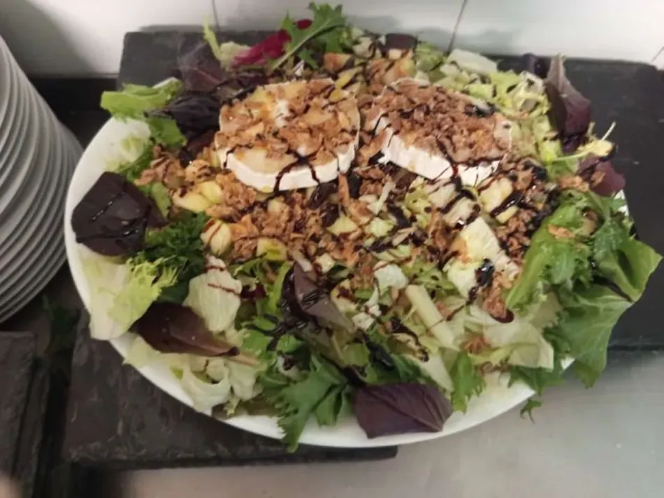 Ensalada cubierta con almendras laminadas y glaseado balsámico en una bandeja.