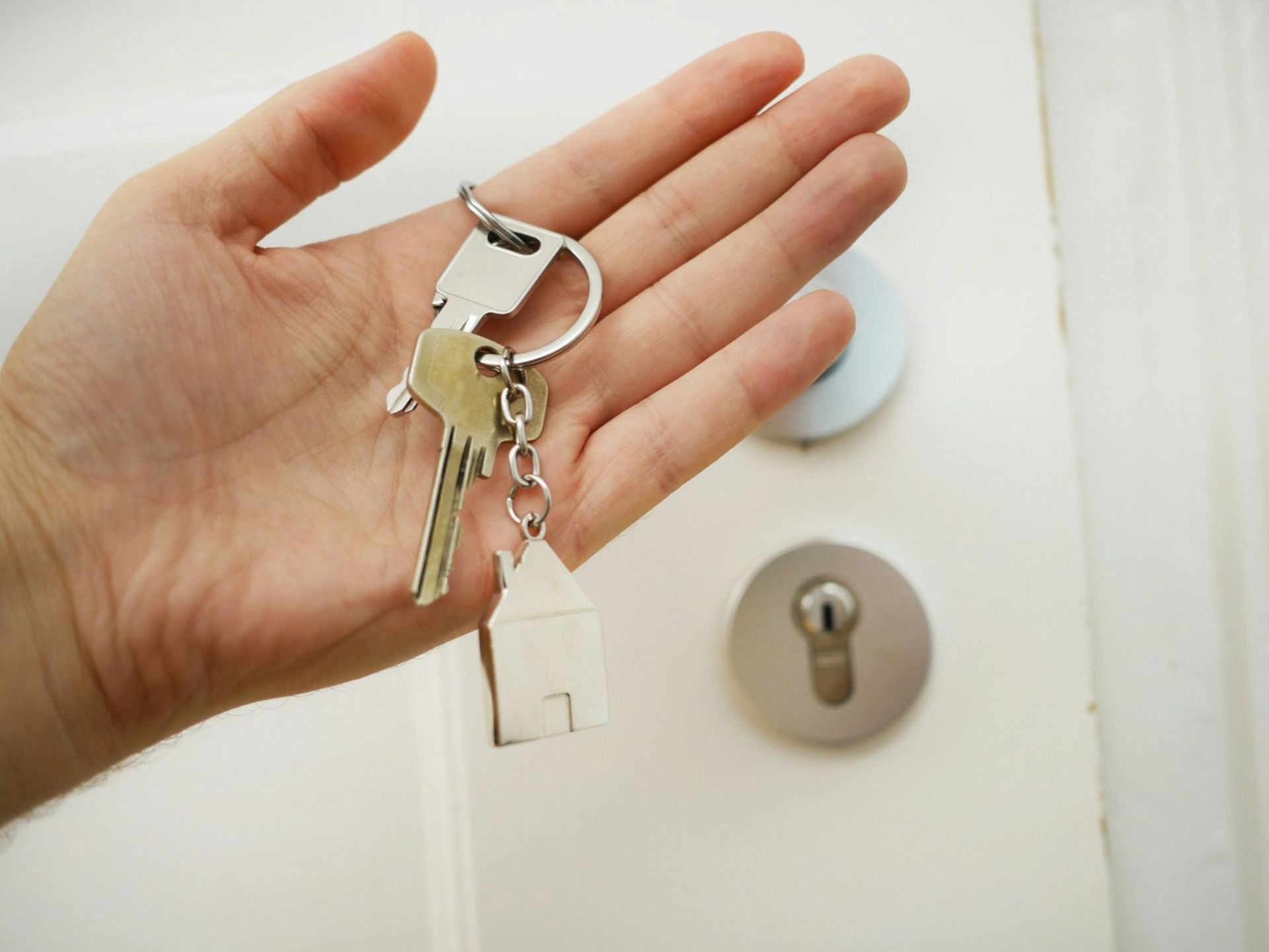 Una persona sostiene un manojo de llaves en su mano frente a una puerta.