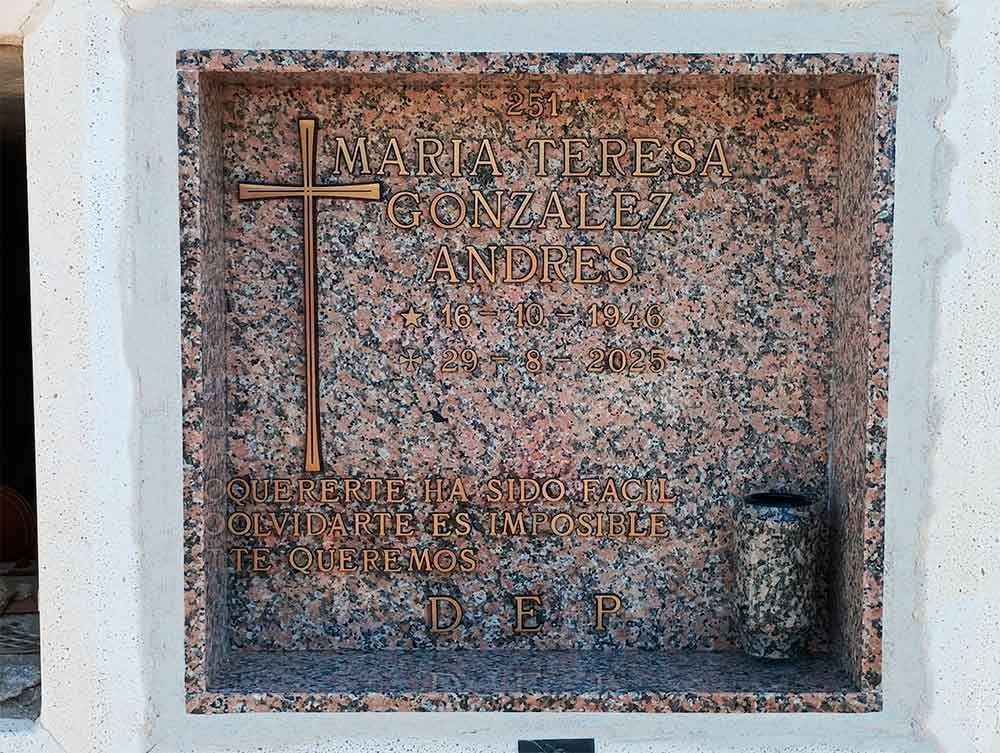 Un nicho conmemorativo de granito con una cruz y una inscripción grabada, posiblemente una tumba.