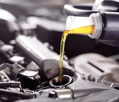 Gros plan d'une personne versant de l'huile dans le moteur d'une voiture.
