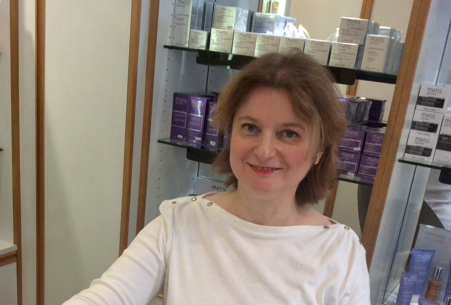 Nathalie Loviat dans son institut, vitrine de produits en arrière-plan